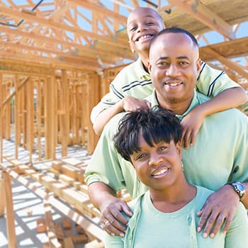 An African American family standing in front of a house being built
