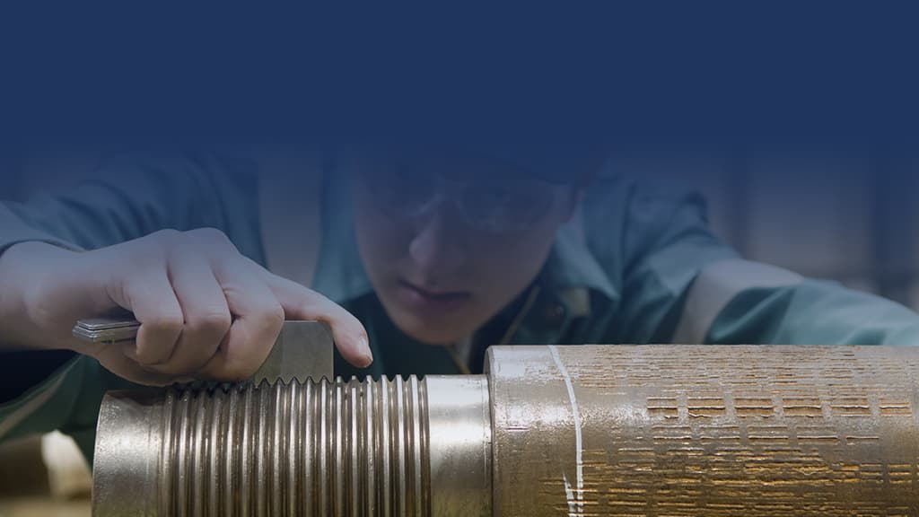 Employee using tool on the teeth of a metal pipe